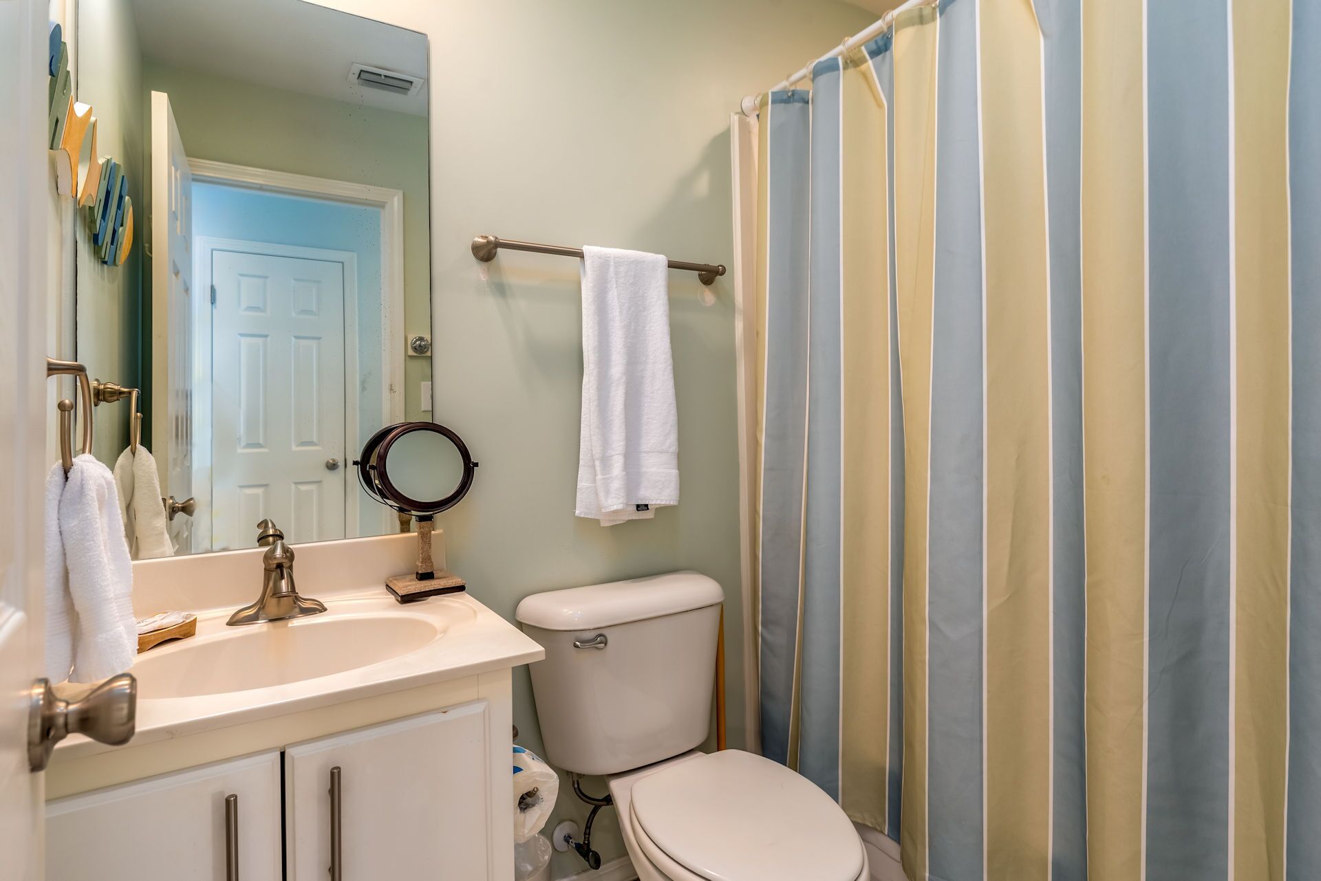 Une salle de bain équipée d’un lavabo, d’un miroir, de toilettes et d’un rideau de douche.