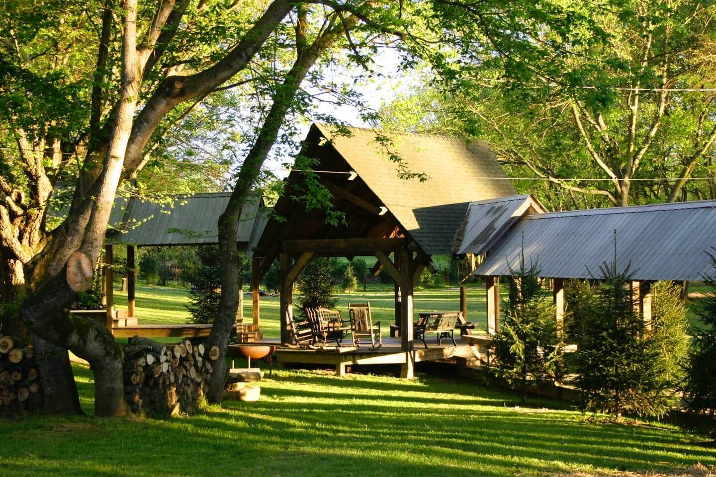 A rustic wooden gazebo with a thatched roof, surrounded by a well-maintained lawn and trees.