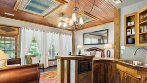 Una cocina acogedora y luminosa, con armarios de madera, una isla central y vistas a un jardín a través del ventanal.