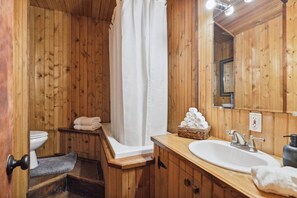 Une salle de bain en bois avec une baignoire, des toilettes, un lavabo et un miroir.