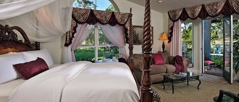 A spacious bedroom with a four-poster bed, a sofa, and a coffee table.