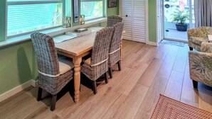 A dining area with wicker chairs and a wooden table, a sliding glass door leading outside, and a potted plant near the door. - Piece of Paradise for All Seasons!!! Bring Your Boat! (St James City)