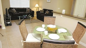A dining area with a round table, four chairs, and a central island with a bowl. - Oakwater Resort, Amazing Location (St. Cloud)