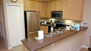A kitchen with wooden cabinets, stainless steel appliances, a granite countertop, and a built-in microwave. - Oakwater Resort, Amazing Location (St. Cloud)