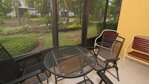A covered outdoor seating area with metal chairs and a table, overlooking a landscaped garden with various plants and a pathway. - Oakwaterresort Near Disney h (St. Cloud)