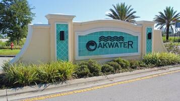 A sign with the name "AKWATER" and a wave symbol, surrounded by greenery and a curved wall.