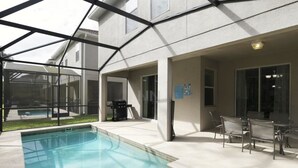 Un espacio al aire libre cubierto con piscina, mobiliario de patio y una parrilla.