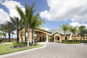 A building with a yellow facade, arched entrance, and palm trees in the foreground.