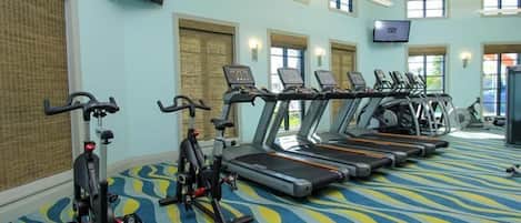 A gym with treadmills, stationary bikes, and a patterned carpet.