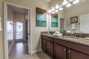 A bathroom with a granite countertop, double sinks, and a large mirror. - Champions Gate Luxury 5 Bedroom Resort Villa (Davenport)