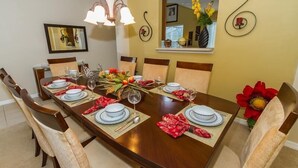 A dining room with a long wooden table set for four, surrounded by cushioned chairs. - Amazing 6 Bedrooms 4 Baths 1028ocb (Bartow)