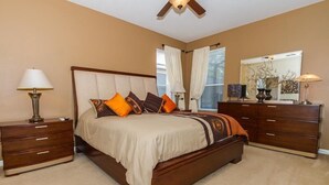 A bedroom with a large bed, wooden nightstands, a dresser, and a ceiling fan. - Amazing 6 Bedrooms 4 Baths 1028ocb (Bartow)