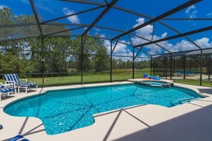 A swimming pool with a clear blue water, surrounded by a covered area with chairs and a hot tub. - Amazing 6 Bedrooms 4 Baths 1028ocb (Bartow)