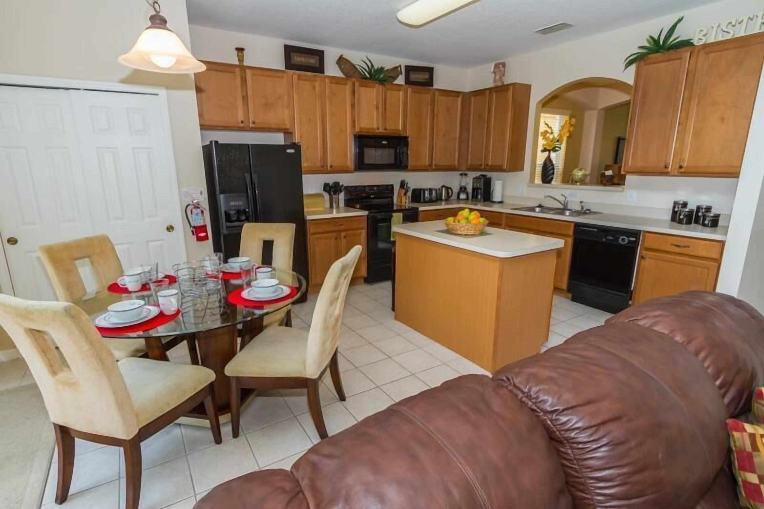 A modern kitchen with wooden cabinets, a central island, and a dining area with a glass table and chairs.
