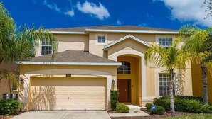 A two-story house with a garage, a front entrance, and a small porch. - Amazing 6 Bedrooms 4 Baths 1028ocb (Bartow)