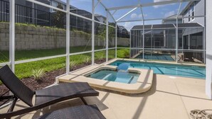 A covered outdoor area with a hot tub, lounge chairs, and a pool. - Amazing NEW 5 Bedrooms Champions Gate! (Davenport)