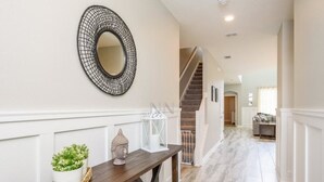 A hallway with a wooden bench, a decorative mirror, and a staircase leading to another room. - Amazing NEW 5 Bedrooms Champions Gate! (Davenport)