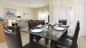 Un coin repas avec une table en verre, dressée pour quatre personnes, entourée de chaises noires.