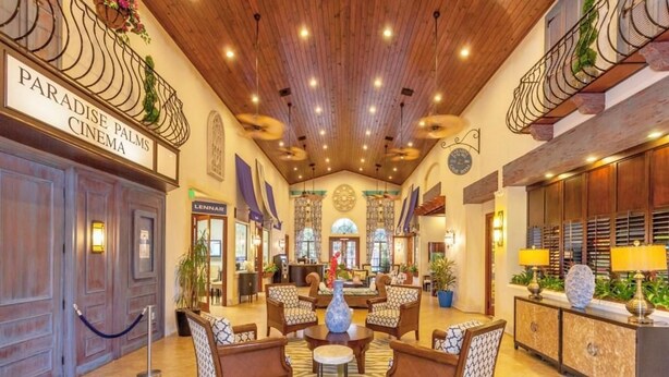 A lobby with a wooden ceiling, a reception desk, seating area, and a sign for Paradise Palms Cinema. - Paradise Palms 6 Bedrooms 5 Baths Best (Kissimmee)