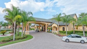 A hotel entrance with a paved driveway, palm trees, and a golf cart. - Paradise Palms 6 Bedrooms 5 Baths Best (Kissimmee)