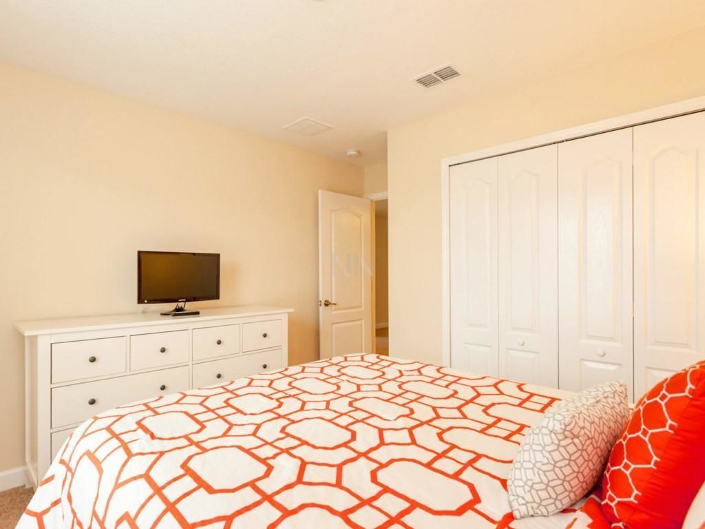 A bedroom with a bed, a dresser, a television, and a wardrobe.
