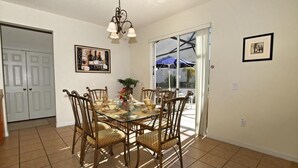 A dining area with a glass table, wicker chairs, and a chandelier. - 103bll Fantastic 4 bed With Games Room (Bartow)