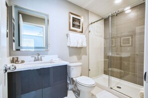 A modern bathroom with a glass-enclosed shower, a white sink, and a large mirror. - 1203lr Beautiful Townhome Close TO Disney (Kissimmee)