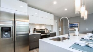 A modern kitchen with stainless steel appliances, white cabinetry, and a central island with a sink. - 1203lr Beautiful Townhome Close TO Disney (Kissimmee)