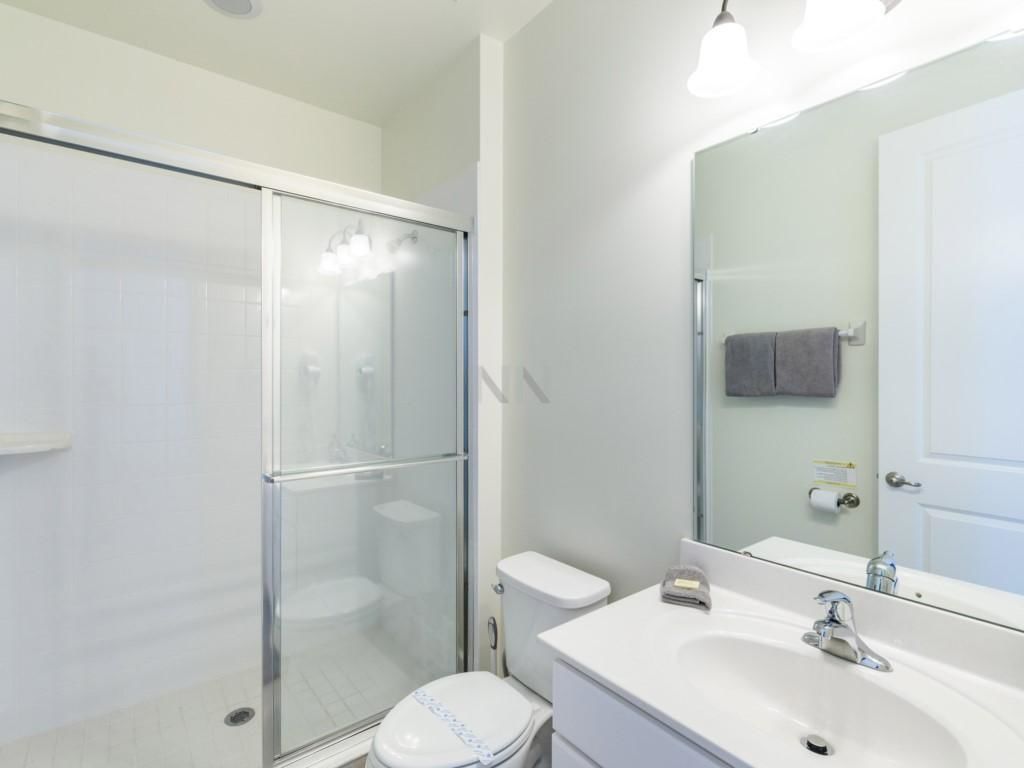 A modern bathroom with a glass shower enclosure, a white toilet, and a sink with a mirror.
