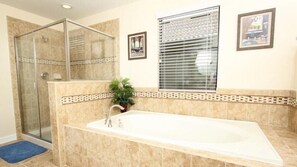 A bathroom with a glass shower enclosure, a bathtub, and a window with blinds. - Champions Gate Luxury 6 Bedroom 1422mvd (Kissimmee)