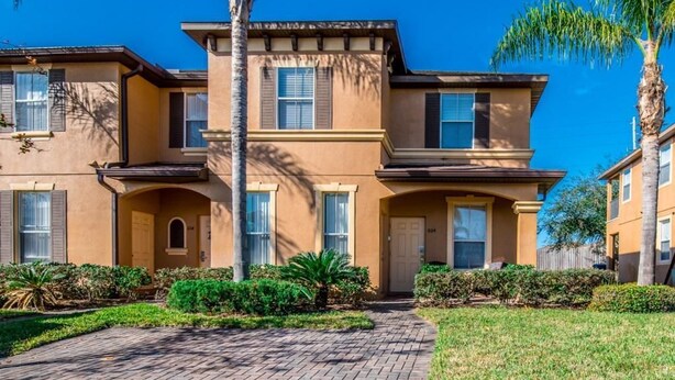 A two-story building with a symmetrical facade, a central entrance, and a paved driveway. - 1104cal 4 Bedroom Townhome in a Resort Waterpark (Bartow)