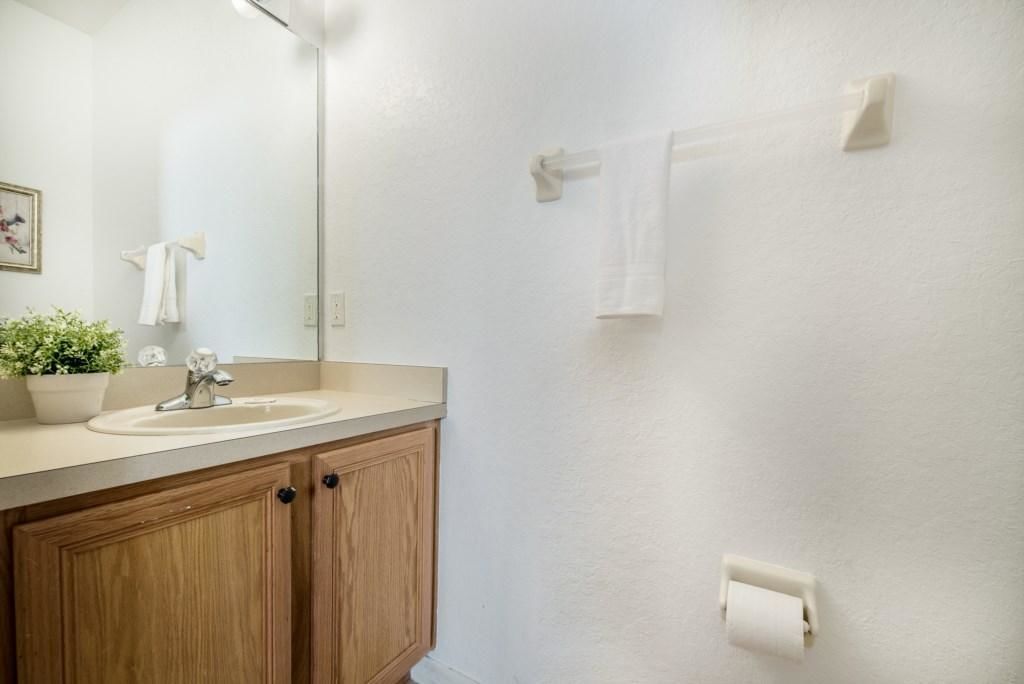Een badkamer met een houten wastafelmeubel, een wastafel, een spiegel en een handdoekrek.