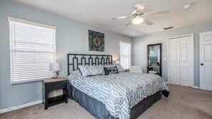 A bedroom with a bed, a nightstand, a ceiling fan, and a window with blinds. - 1104cal 4 Bedroom Townhome in a Resort Waterpark (Bartow)