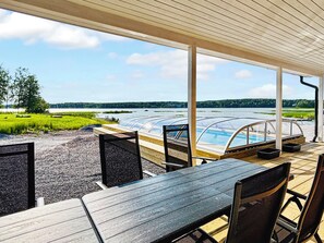 Un espacio al aire libre techado con vistas a un lago, una piscina y un muelle.