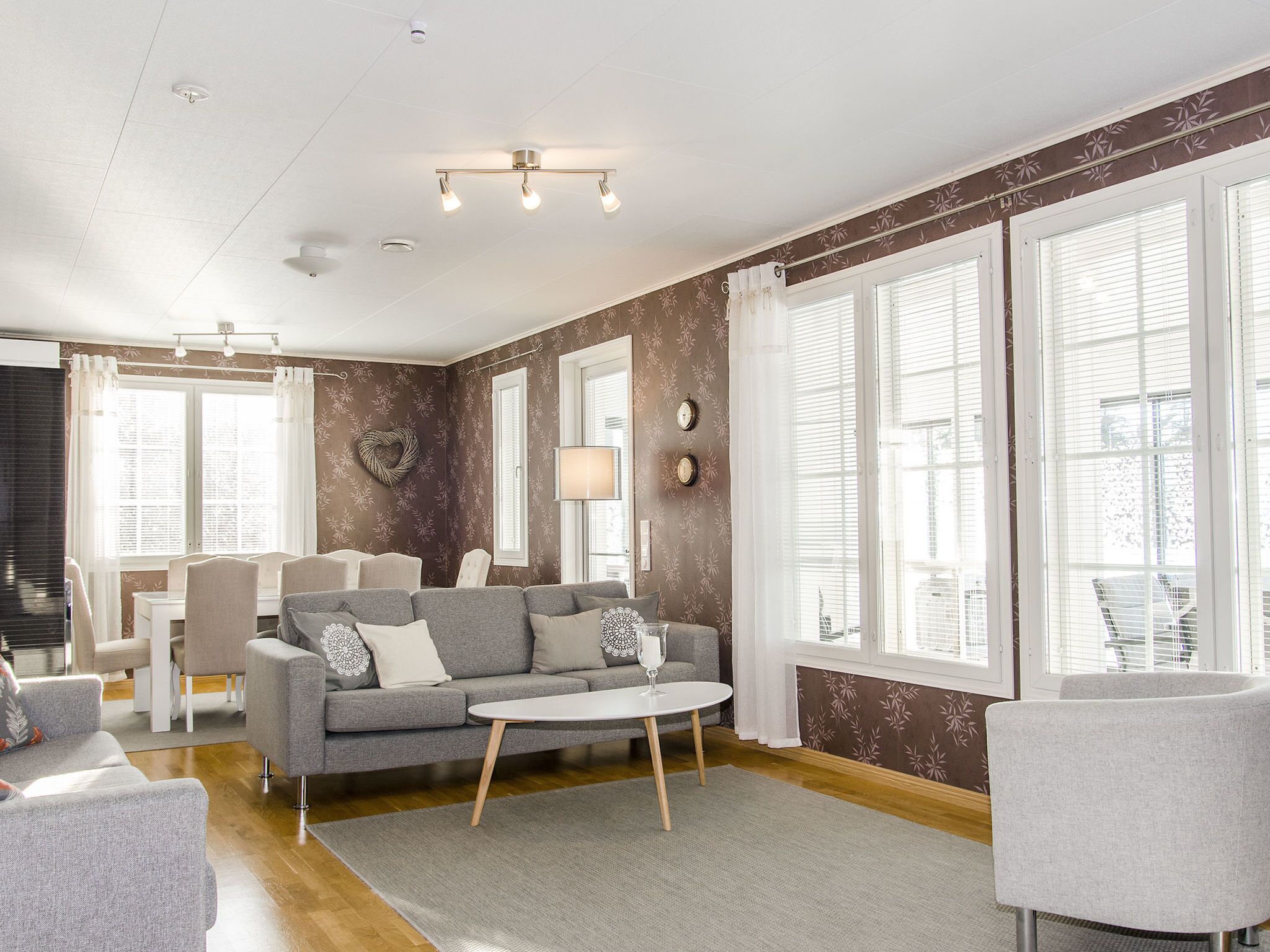 A modern living room with a grey sofa, a round coffee table, and a dining area with a white table and chairs.