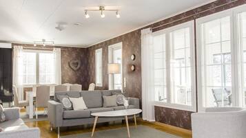 A modern living room with a grey sofa, a round coffee table, and a dining area with a white table and chairs.