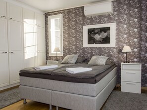 Un dormitorio con cama, mesita de noche, cómoda y ventana con persianas.