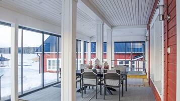A spacious room with large windows, a wooden floor, and a table with chairs.