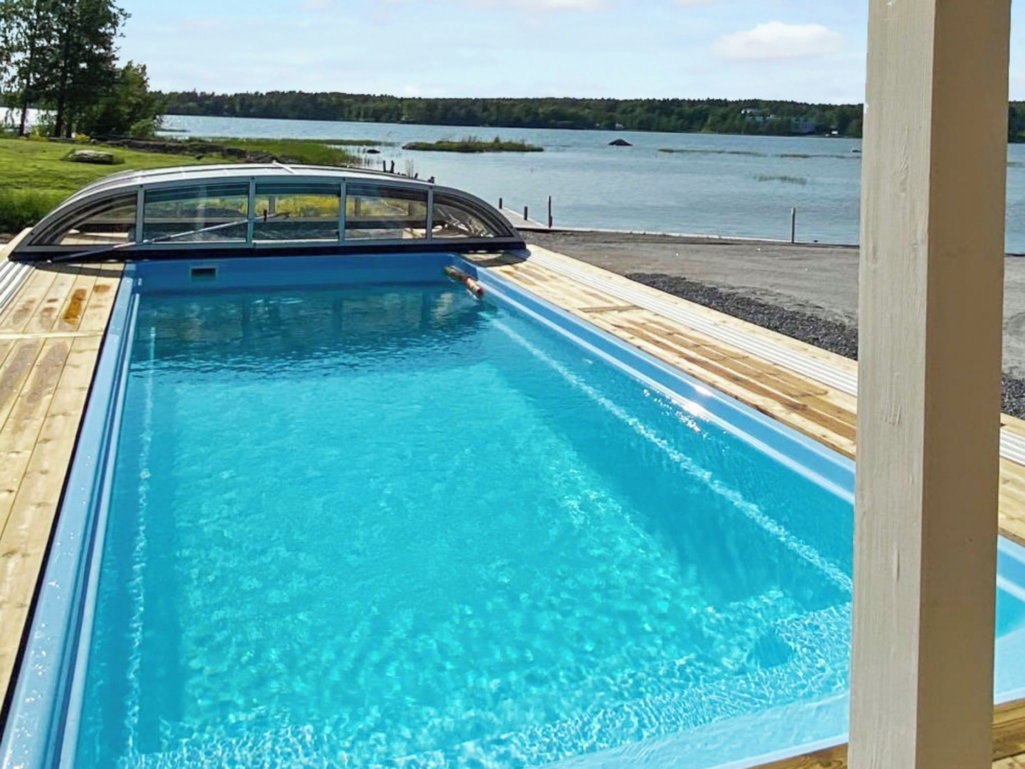 En swimmingpool med ett trädäck och utsikt över en sjö.