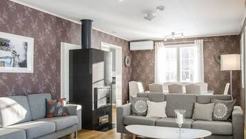 A modern living room with two grey sofas, a white coffee table, a black fireplace, and patterned wallpaper.