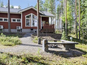 Une cabane dotée d’un porche, entourée d’une forêt.