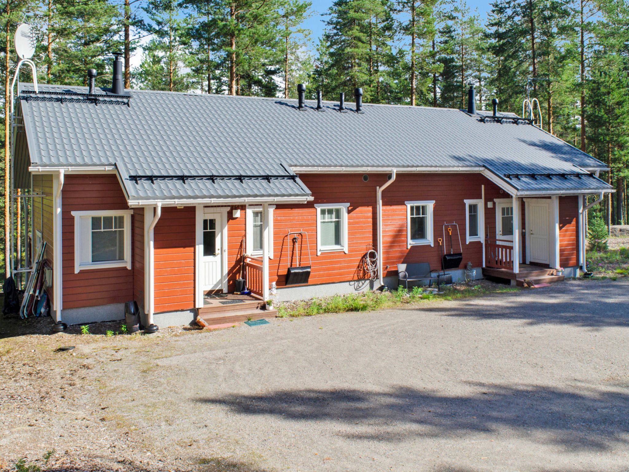 Eine zweistöckige Holzhütte mit einem Metalldach, einer Veranda und einer kleinen angebauten Garage.