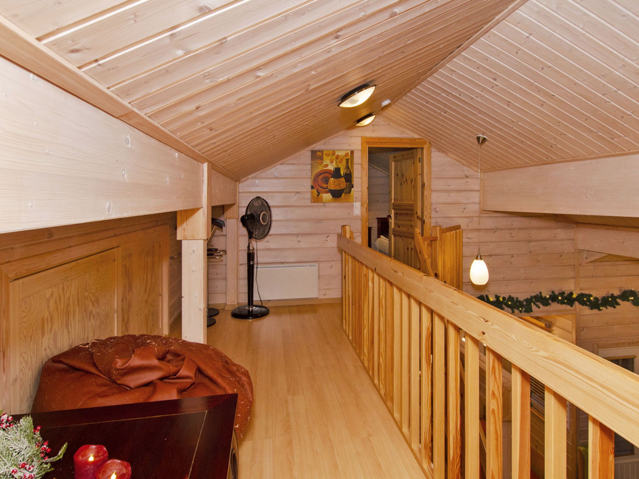Un interior de madera con techo y barandilla de madera, y vista a una habitación contigua.