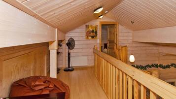 Un interior de madera con techo y barandilla de madera, y vista a una habitación contigua.