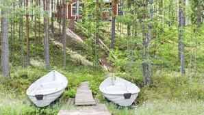 A wooden dock leading to two boats, surrounded by a forest with a cabin in the background. - Otsopirtti, maria by Interhome (Lieksa)