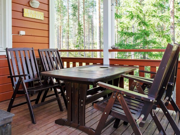 Une terrasse en bois avec une table et des chaises, donnant sur une forêt.