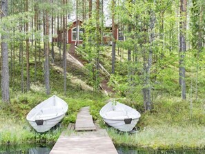 Escape to a serene lakeside retreat, where a wooden dock leads to a cozy cabin nestled among tall trees.
