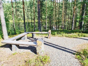 Une table de pique-nique avec des bancs, située dans une zone boisée.