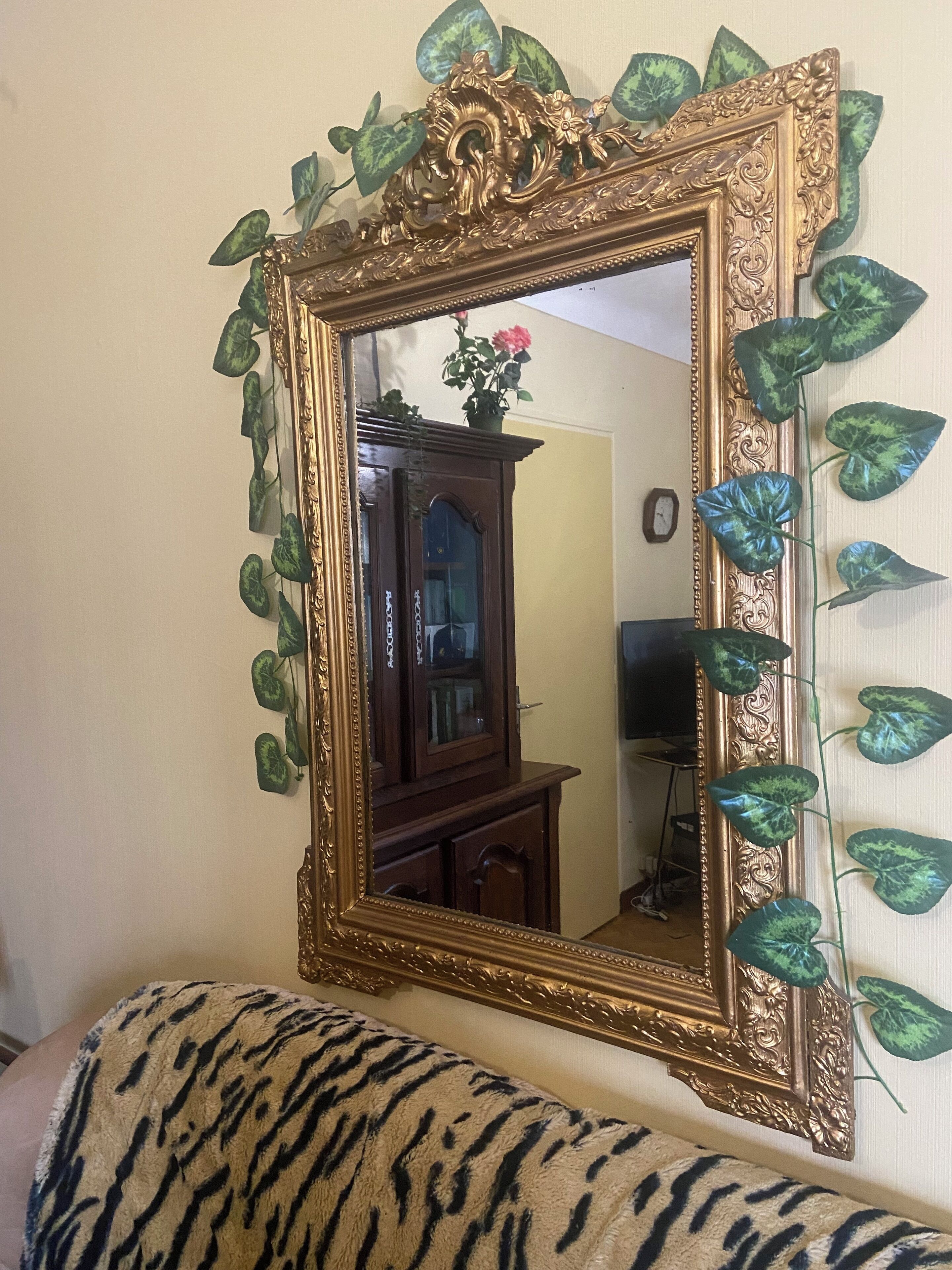 A room with a large ornate mirror, a wooden cabinet, and a tiger-patterned sofa.
