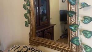 A room with a large ornate mirror, a wooden cabinet, and a tiger-patterned sofa. - Maison Corisande, near the entrance to Bagnères de Bigorre (Gerde)